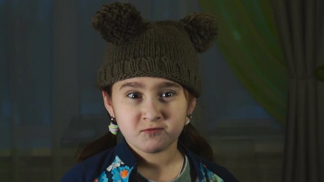 the girl in a cap with pompons makes ridiculous faces