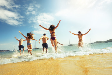 Big group of friends runs at sea beach. Tropical vacations concept