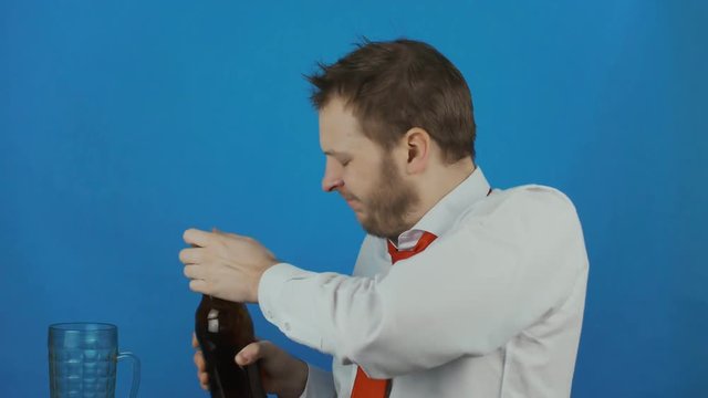 unshaven careless man like a alcoholic pours beer into a mug and drinks ale or lagger