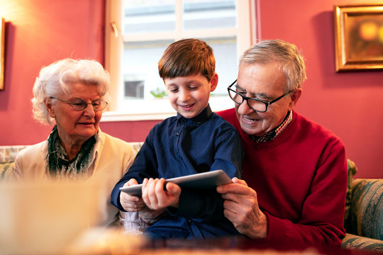 Grandson teaching his grandparents how to use a tablet
