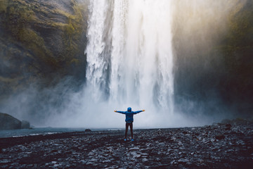 A person admirnig the beauty of Skogafoss waterfall located in Iceland