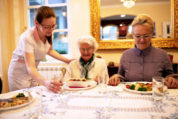 Caring nurse serving meals for dinner