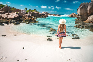 A young girl standing in shallow water on La Digue island, Seychelles - obrazy, fototapety, plakaty