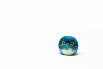 Lucky owl ornament. Small glass lucky object, charm. Blu, azzurro, lilla, viola, giallo. Isolated on white background. Tradition has it that a pair (couple) of owls bring luck.