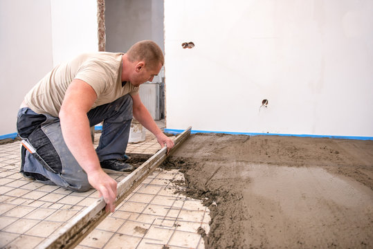 bricklayer aligns cement screed in a newly built house