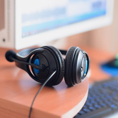 Fototapeta na wymiar Big black headphones lie on the wooden desktop of the sound designer