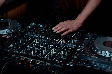 Hands of female DJ adjusting sound during disco party. Entertainment concepts equipment 