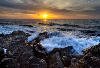 Obraz premium Stormy sea with the colorful sunrise sky at the rocky coastline of the Black Sea