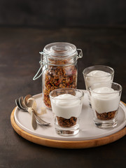 Healthy breakfast. Fresh granola, muesli in a glass with yogurt walnuts, goji berries and raspberries on dark background. Copy space.