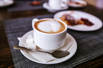 Cappuccino in a white cup. Fresh morning aromatic breakfast.