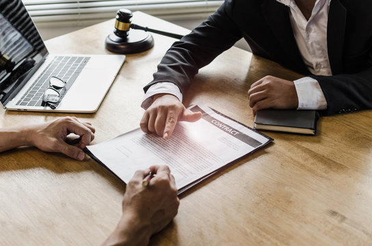 client customer signing contract and discussing business with legal consultants, notary or justice lawyer with laptop computer and wooden judge gavel on desk in courtroom office, legal service concept