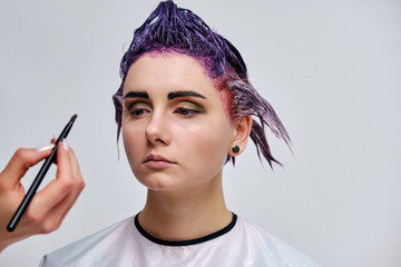 Obraz premium Beautiful girl with violet hair on white background master in make-up.