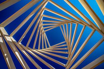 .swirled ceiling of a wooden gazebo on the background of blue and clear sky