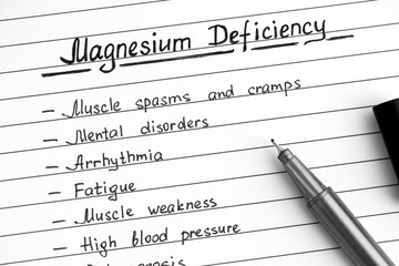 Symptoms of Magnesium Deficiency writing on list with black pen.