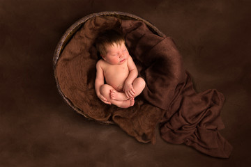 Baby sleeping in old wooden  bowl