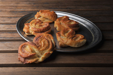 Buns heart shaped puff pastry with cinnamon on metal tray