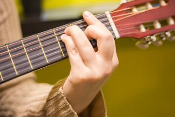 Lesson playing the guitar. The girl practices music. Playing a six-string acoustic guitar. Musical...