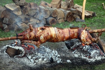Suckling pig on a rotating spit with fire in the background