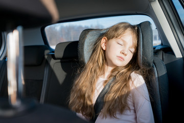 Sleeping little girl in child car seat during long journey