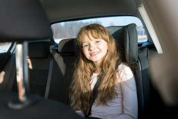 Fototapeta na wymiar Happy little girl in child car seat
