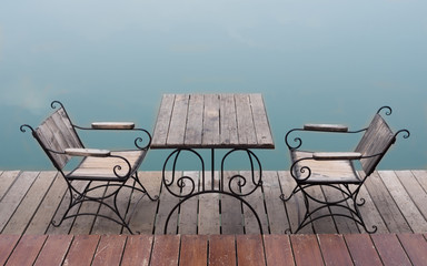 Wooden table and chairs near lake.