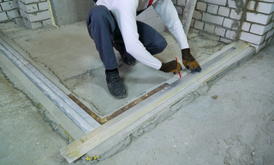 construction worker doing markup with measuring standard at construction site