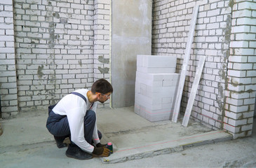 construction worker doing measures with laser level at construction site