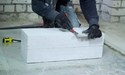 construction worker doing markup on aerated concrete block at construction site