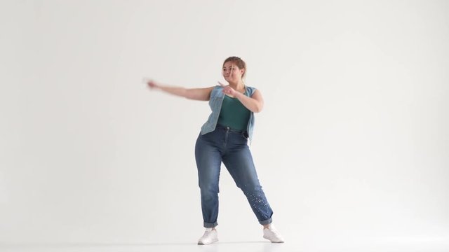Fat young woman dancing on studio background