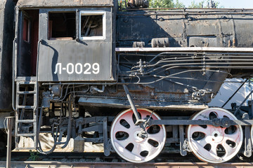 Old rusty steam locomotive beside a railway station platform. Retro train.