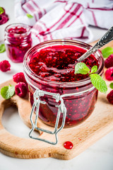 Homemade raspberry jam in two jars with raspberries and mint