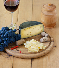 Kachotta cheese on a wooden board on a wooden background with wine in a glass, honey and grapes