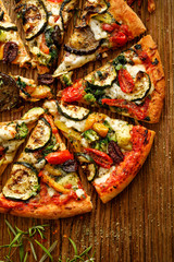 Vegetarian pizza with addition grilled vegetables and aromatic herbs, divided into portions on a...