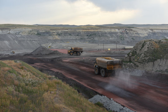 Inside of an open pit coal mine, large water trucks are spraying water on roads to control dust, in the Powder River Basin of Wyoming, USA. 