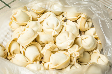 Fototapeta na wymiar Handmade siberian dumplings are in plastic bag on table.