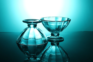 Two transparent bowls glow and reflect on a green background.