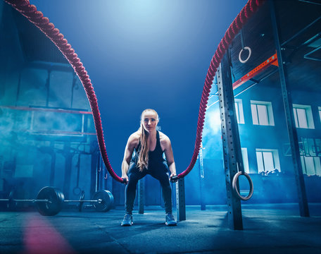 Woman with battle rope battle ropes exercise in the fitness gym. CrossFit concept. gym, sport, rope, training, athlete, workout, exercises concept