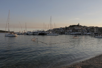 Fototapeta premium View of the marina and the old town in Primosten. Sailboats, yachts on the Adriatic Sea. Warm, summer, evening on the Croatian coast. Mediterranean vegetation, riviera, sunset, Croatia