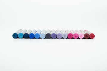 Pastel crayons lined up on a white background