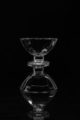 two transparent glass vases on top of each other on a black background and their reflection