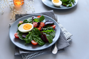 Salad mix with spinach, arugula,beet leaves, tomatoes and eggs on gray wooden background. Vegetarian food concept. Selective focus.