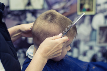 Little boy does a haircut at the hairdresser. Baby hair care.