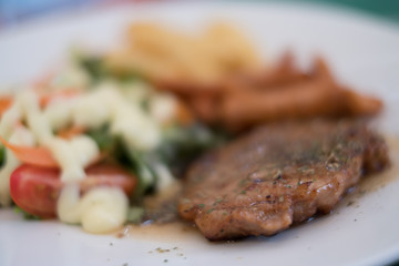 Soft focus of pork steak on dish.