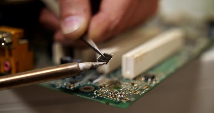 smoking soldering iron on a computer motherboard closeup