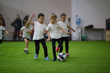 Children playing football indoors. Children lead the ball