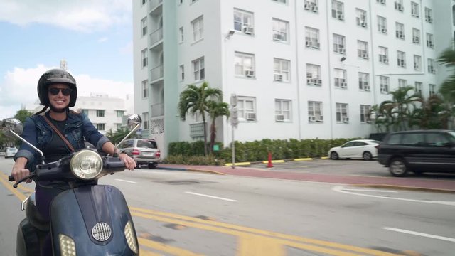 Young woman riding vintage scooter in sunny city