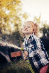Young girl spraying water with a hose