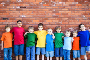 Obraz premium Group of Boys Leaning Against Brick Wall Outside