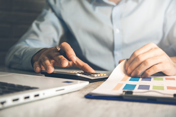 man hand calculator with graph on desk