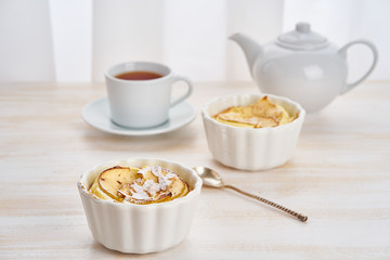 Apple cake and cup of tea on white wooden table in kitchen. Delicate curd dessert with apples, almond flakes and cinnamon, side view